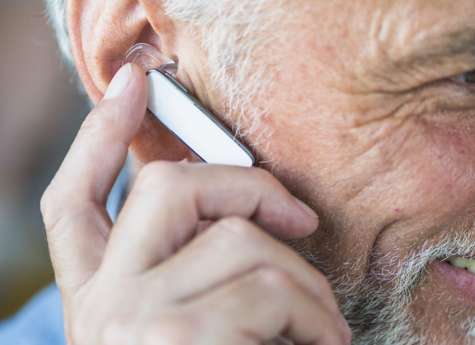 Um senhor idoso utiliza aparelho no ouvido conectado via bluetooth.